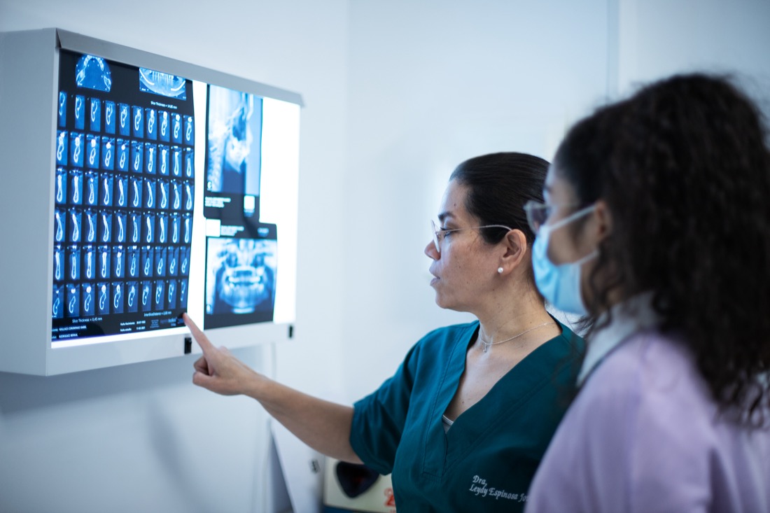 Dra. Leydy Espinosa Jovel revisando una radiografía panorámica y CBCT junto a una compañera